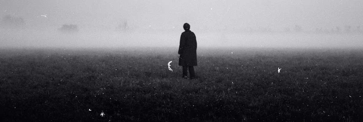 مرد تنها در طبیعت ترسناک و با فاصله زیاد از دوربین تصویربرداری سیاه و سفید وسط مه