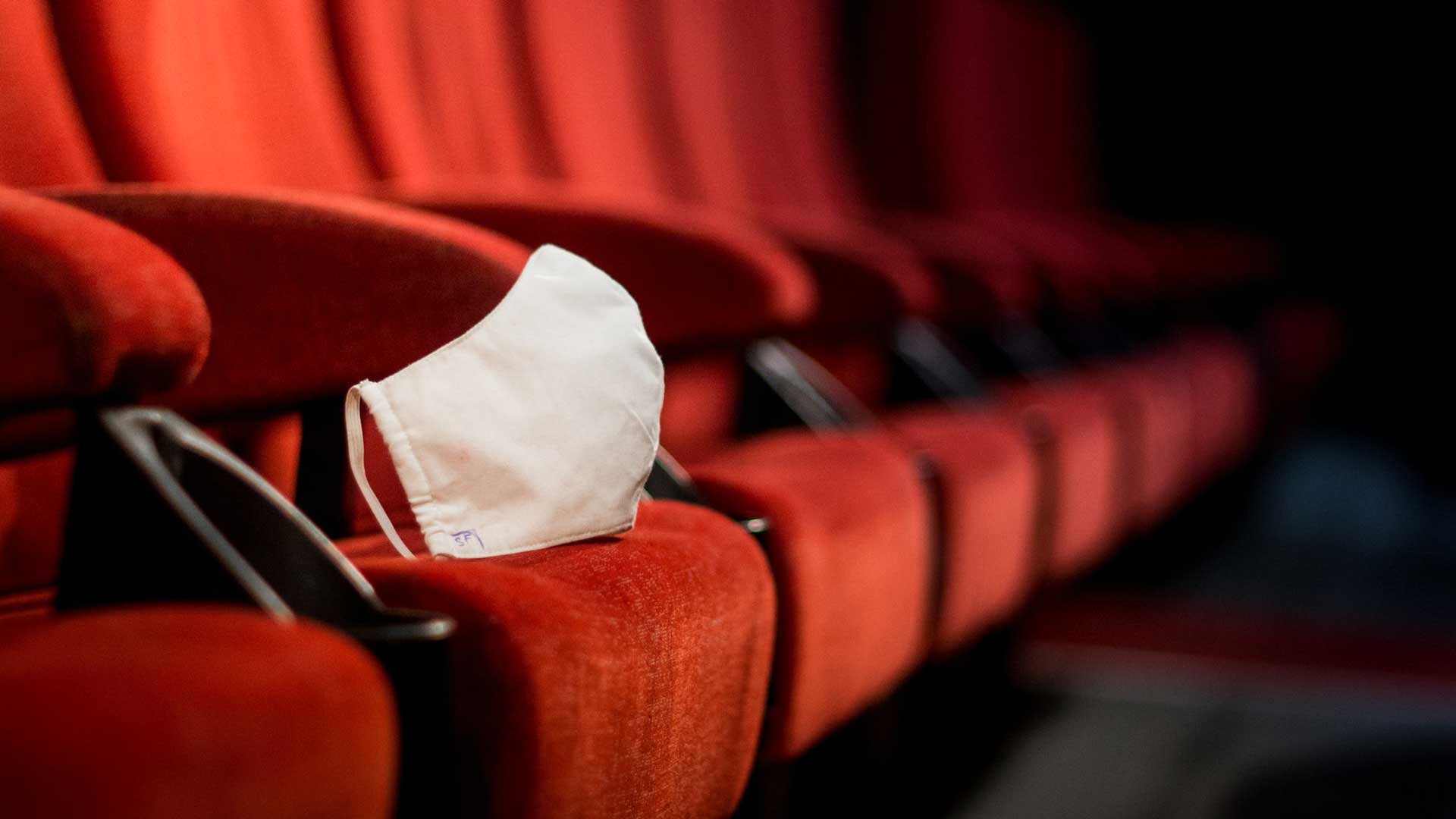 تصویر صندلی های قرمز و خالی سینما با رنگ قرمز و یک ماسک سفید