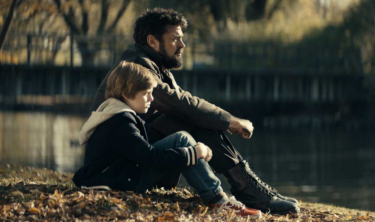 کارل اربن در نقش بیلی بوچر نشسته کنار فرزند بکا و مشغول نگاه انداختن به دریاچه در فصل دوم سریال The Boys شبکه آمازون