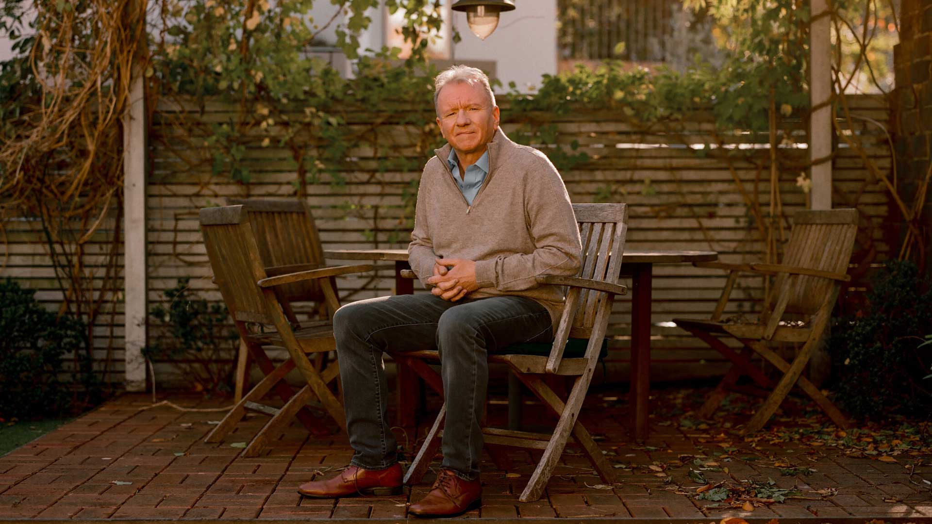 جیم رایان، مدیر برند پلی استیشن شرکت سونی نشسته روی صندلی در فضای آرام حیاط