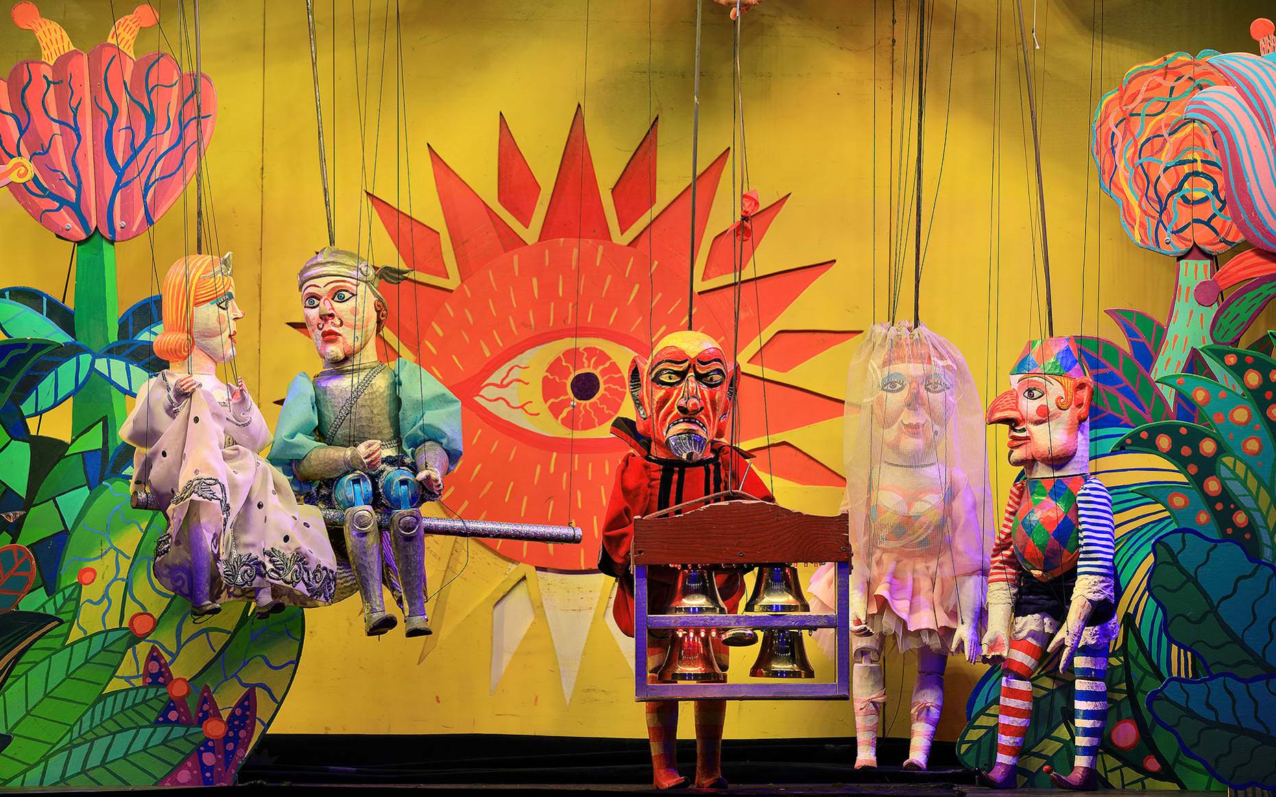 marionette  ها در نمایش عروسکی و تصویر خورشید و تک چشم در پشت زمینه صحنه تیاتر