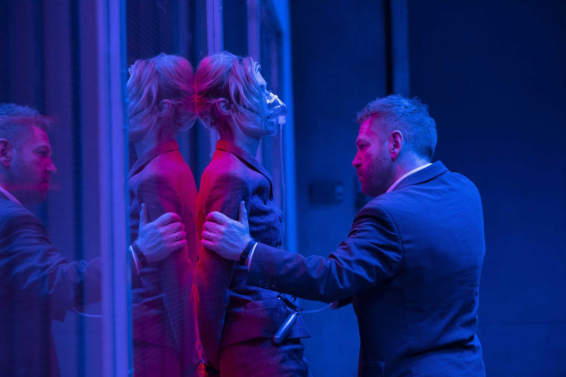 آندری سیتور با بازی کنت برانا مشغول نشانه گرفتن تفنگ به سمت کت با بازی الیزابت دبیکی در اتاق آبی فیلم Tenet کریستوفر نولان