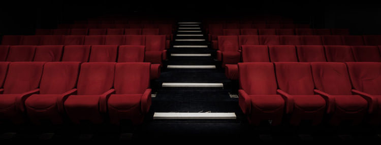 صندلی های قرمز سینما خالی ترسناک با راه پله سفید و سیاه