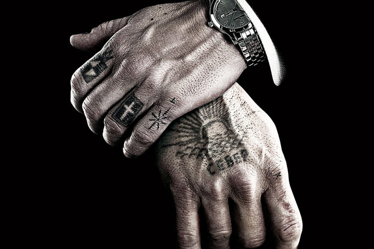دو دست انسان با خالکوبی/تتو به همراه یک ساعت نقره ای گران قیمت در فیلمی از دیوید کراننبرگ