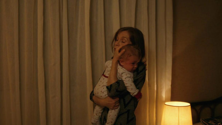 مادر در حال در آغوش گرفتن نوزاد خسته مقابل پرده سفید و چراغ خواب خانه در فیلم Things to Come