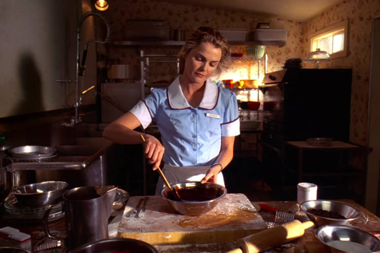 زنی در حال پختن کیک با لباس آبی در اتاق کم نور در فیلم Waitress