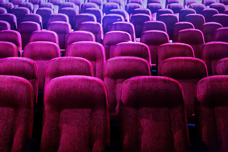 صندلی های سرخابی و بنفش خالی در سالن سینما