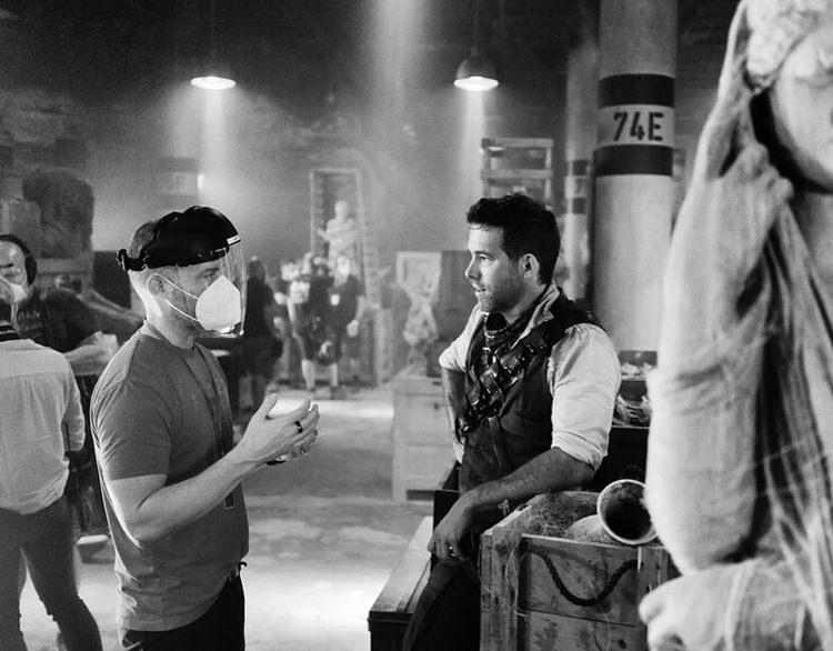 رایان رینولدز مشغول گفت‌وگو با راوسون مارشال تربر  سر صحنه‌ی فیلمبرداری Red Notice 