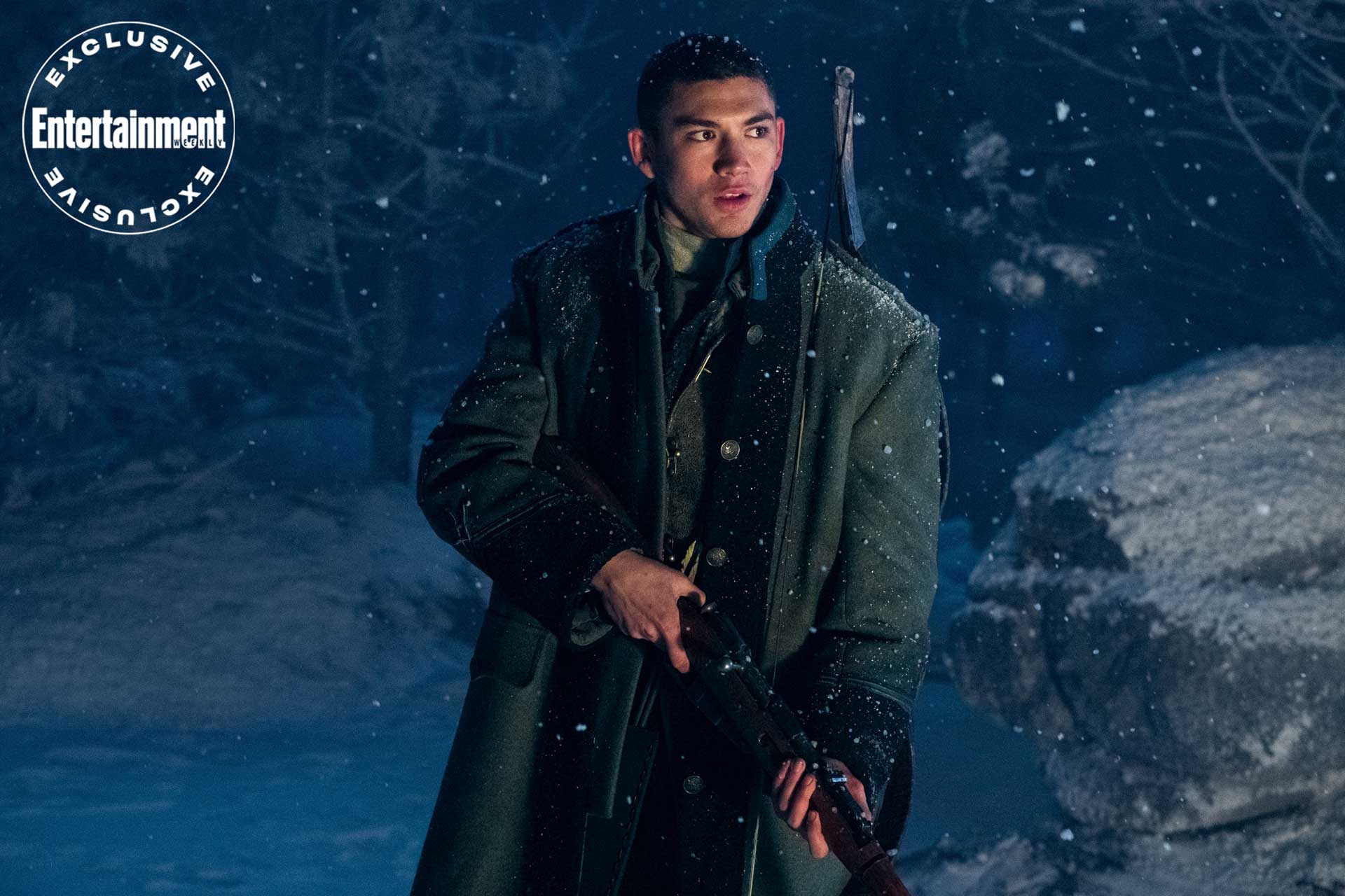 پسر جوان با تفنگ بزرگ و کت بلند در میان برف سریال Shadow and Bone شبکه آنلاین نتفلیکس