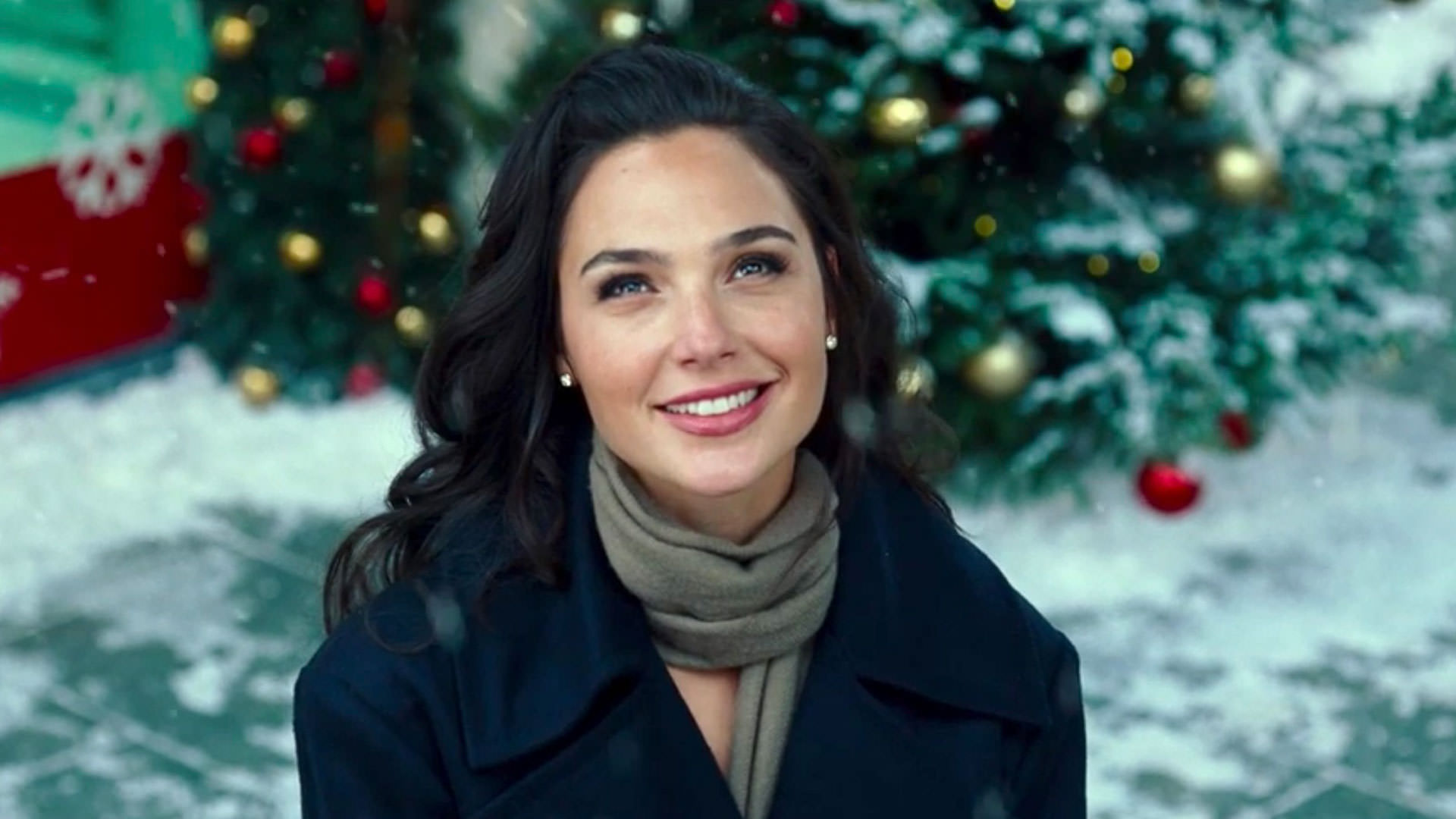 لبخند گدوت زیر برف و جلوی درختان تزئین شده در Wonder Woman 1984