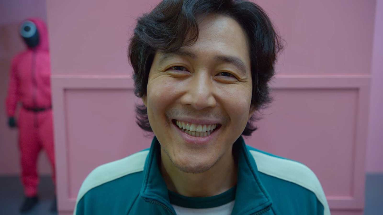 مرد کره ای مشغول لبخند زدن موقع نگاه به دوربین در سریال Squid Game نتفلیکس