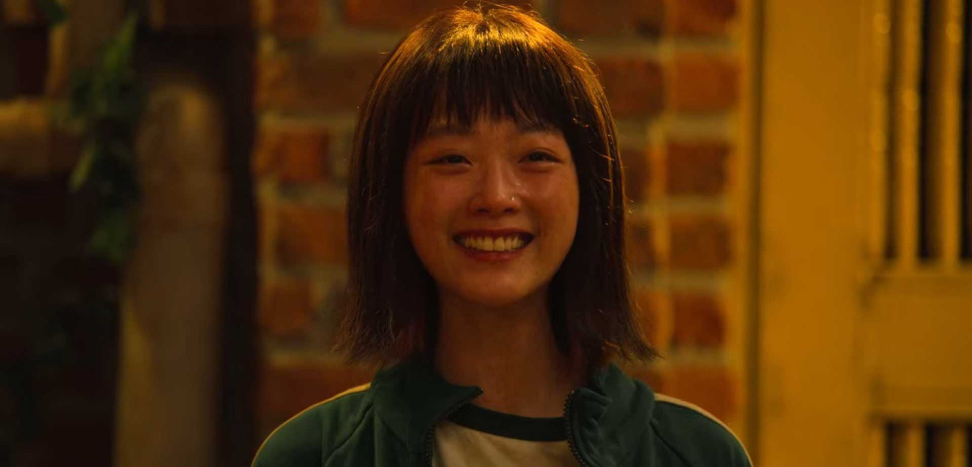 اشک و لبخند دختر کره‌ای مقابل دیوار آجری در سریال Squid Game شبکه نتفلیکس