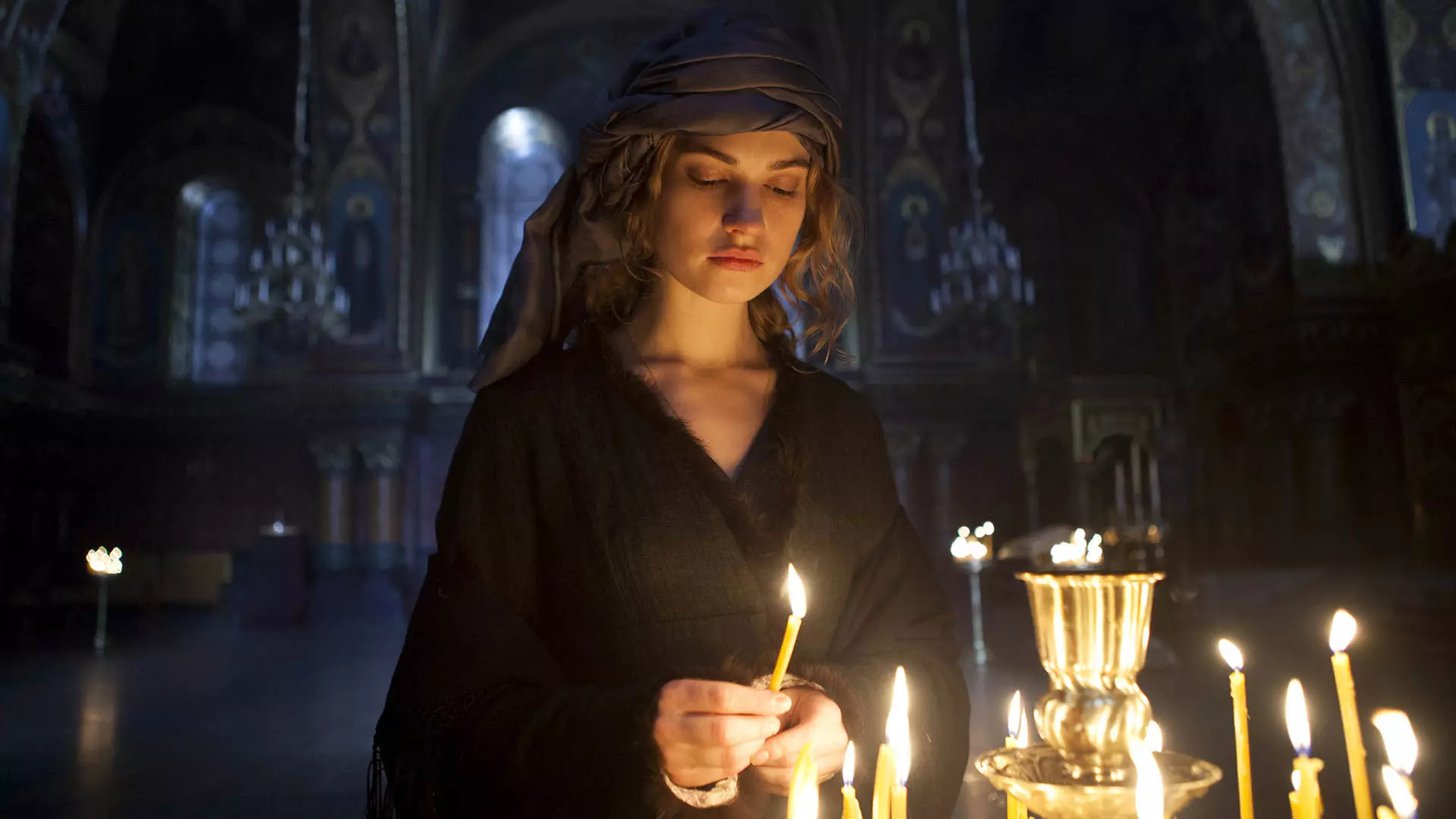 لیلی جیمز در حال روشن کردن شمع در مینی سریال War & Peace
