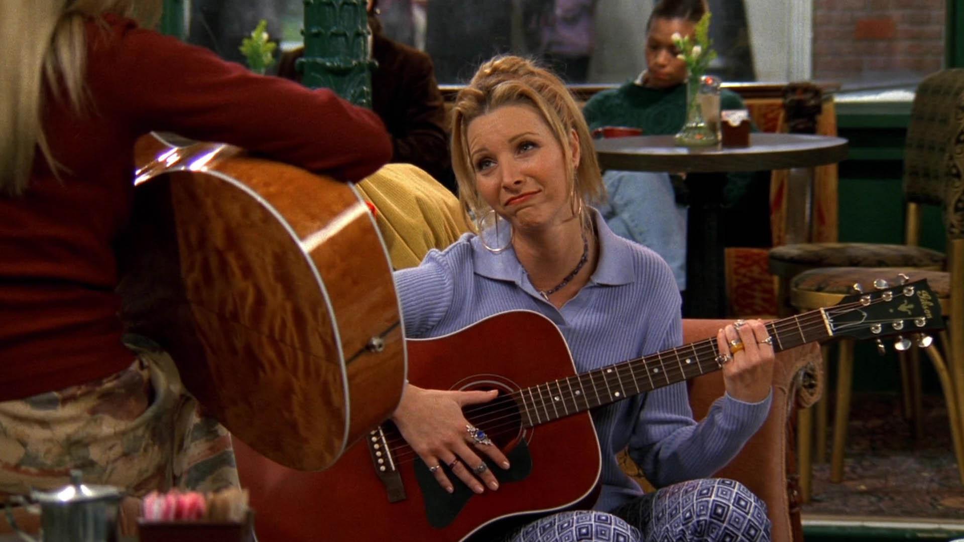 شخصیت فیبی بوفی درحال گیتار زدن با بازی لیسا کودرو در سریال Friends