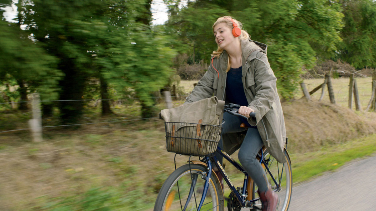 فیلم The Bélier Family از سینمای فرانسه و دختر در حال گوش دادن به موسیقی و دوچرخه سواری کنار درختان