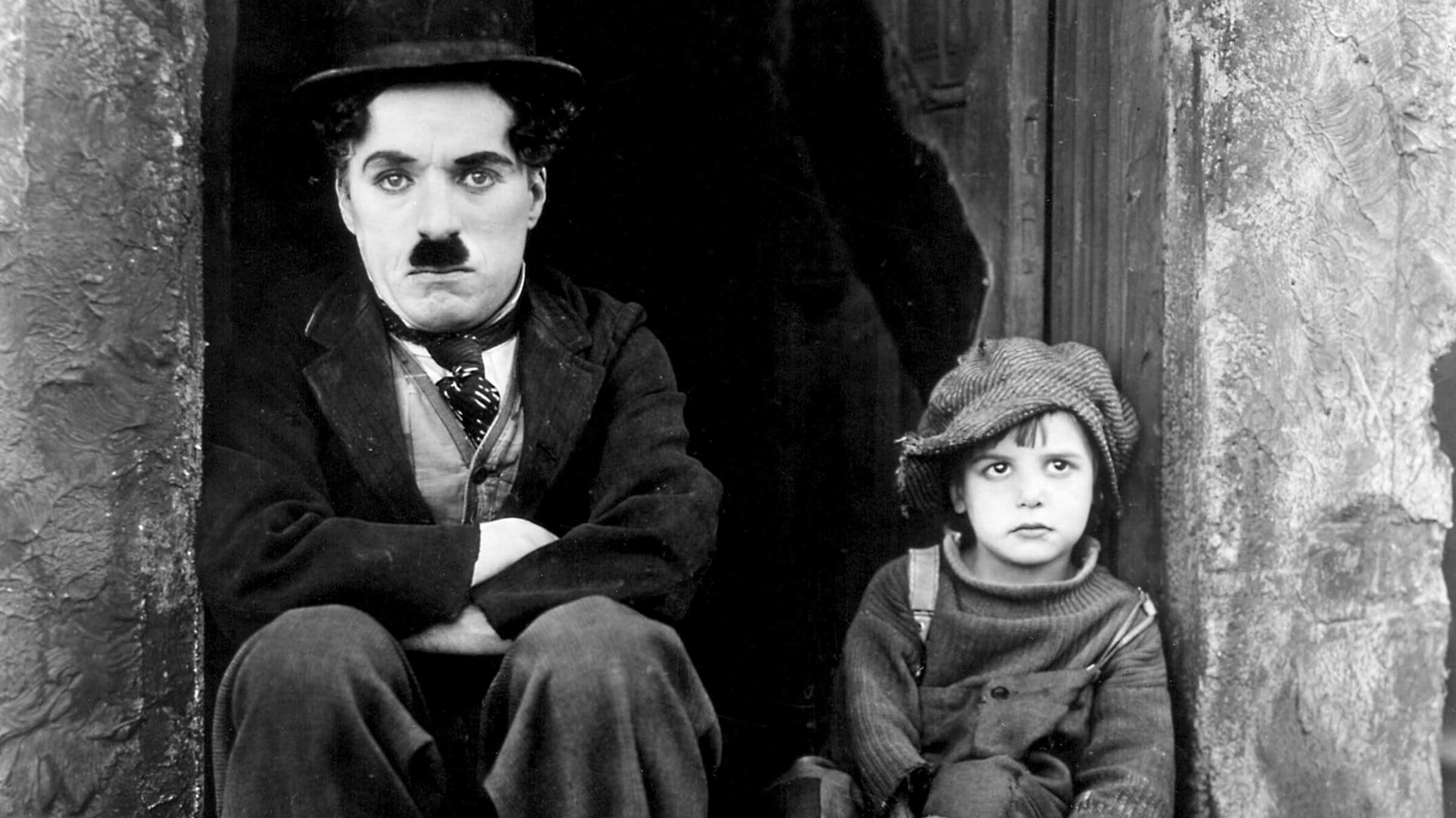 چارلی چاپلین با سبیل خاص کنار بچه در فیلم سیاه و سفید کلاسیک The Kid