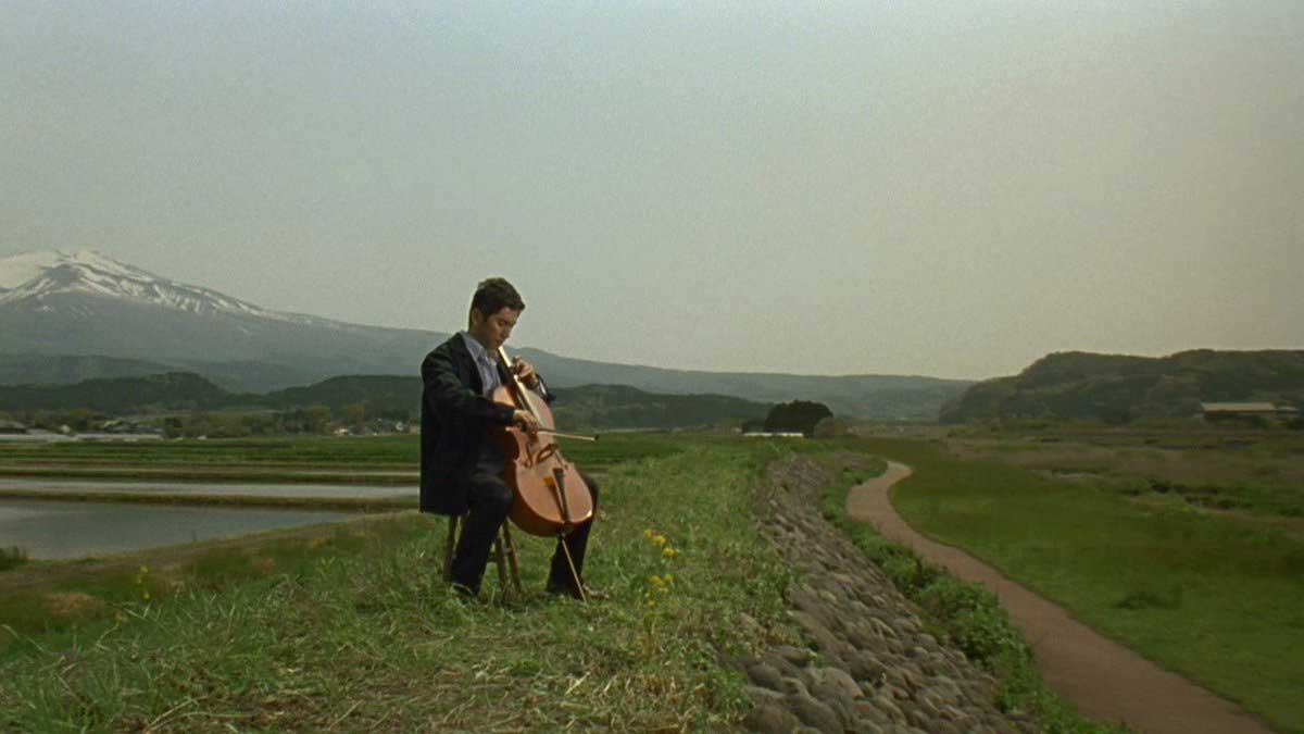 مرد در حال نواختن موسیقی در حاشیه جاده فیلم ژاپنی Departures