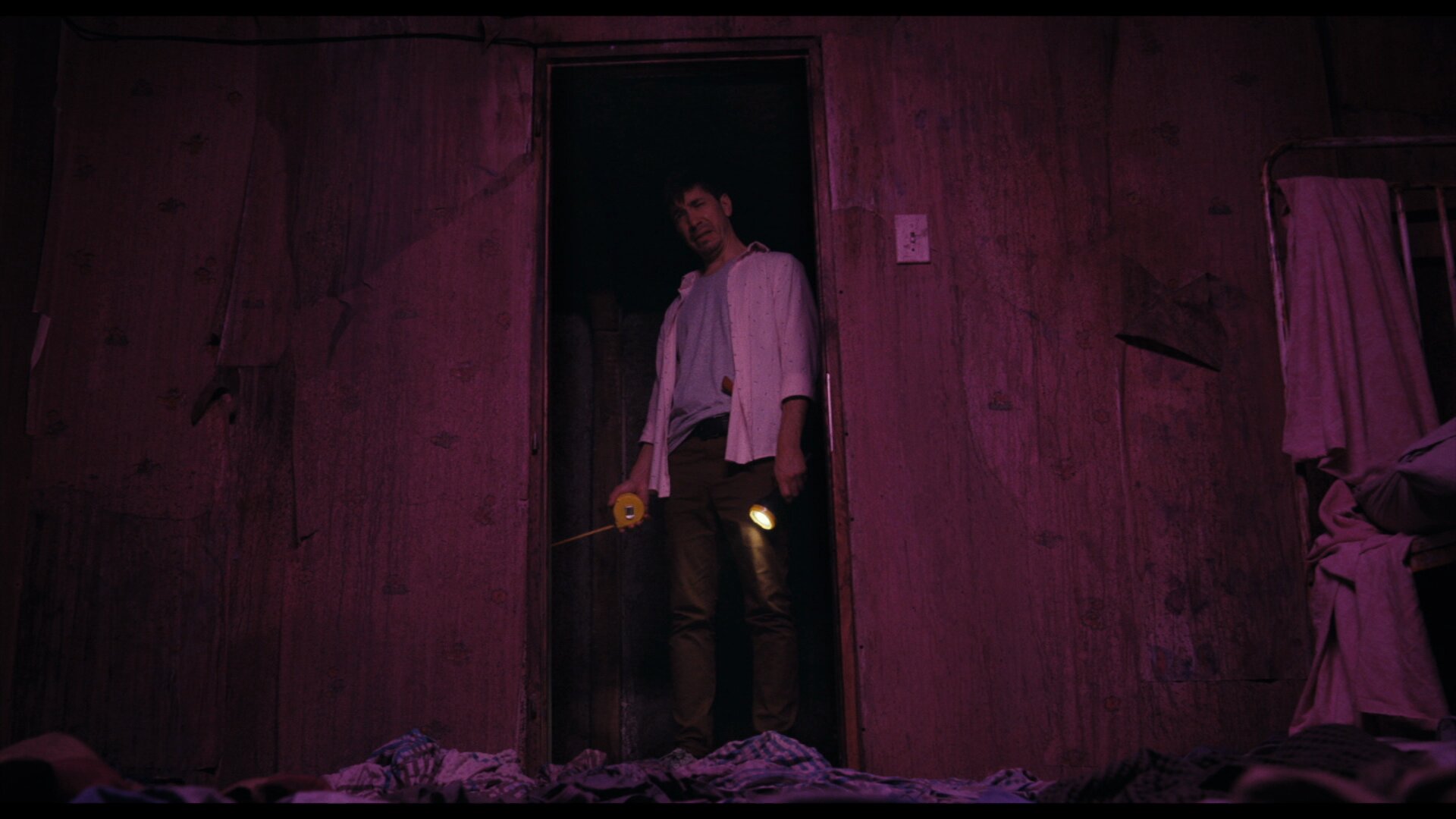 Justin Long mesurant l'étrange sous-sol de sa maison dans le film Barbarian