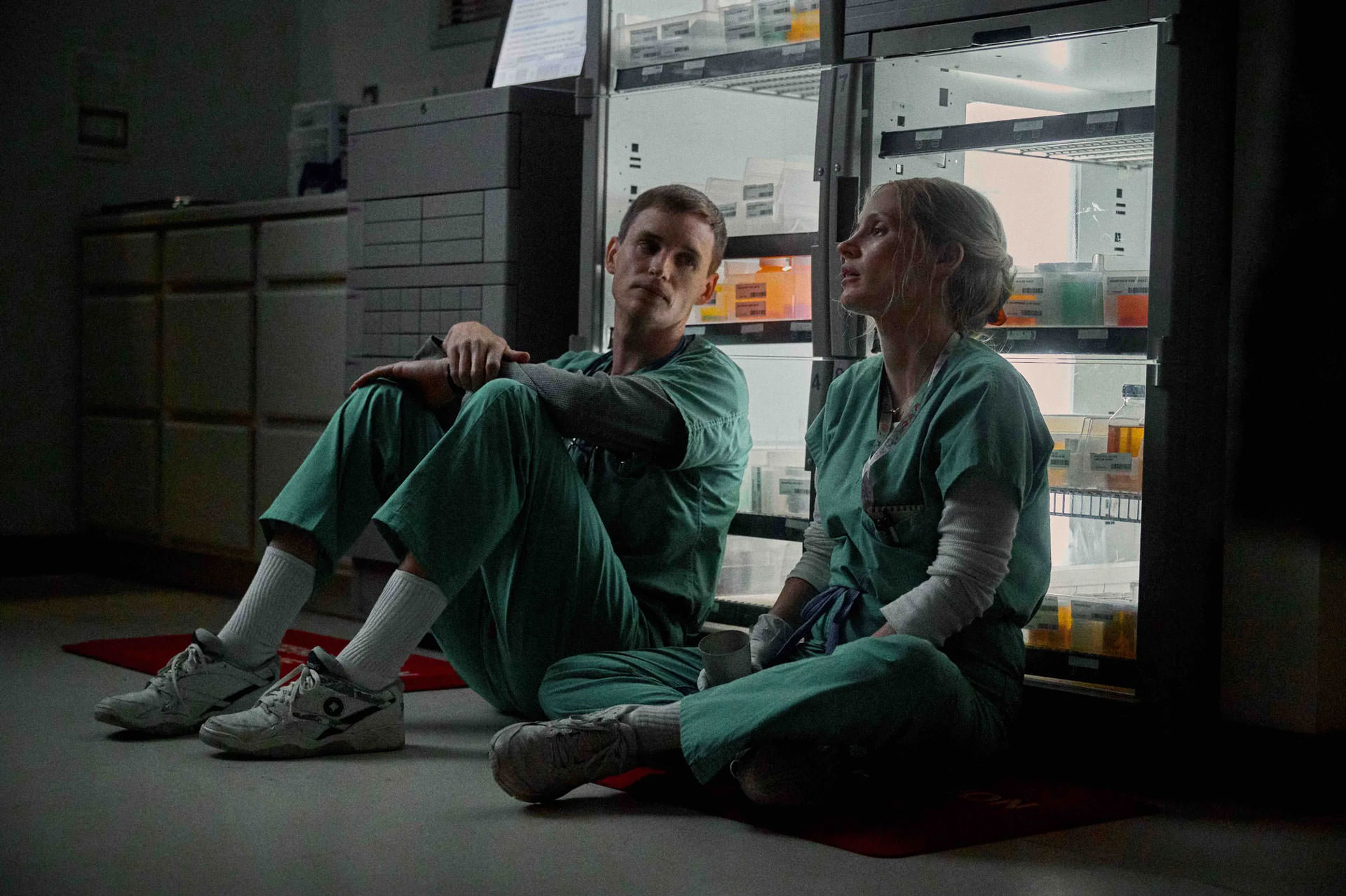 Jessica Chastain assise à côté d'Eddie Redmayne devant un dispositif de stockage de médicaments dans une scène du film The Good Nurse réalisé par Tobias Lindholm.