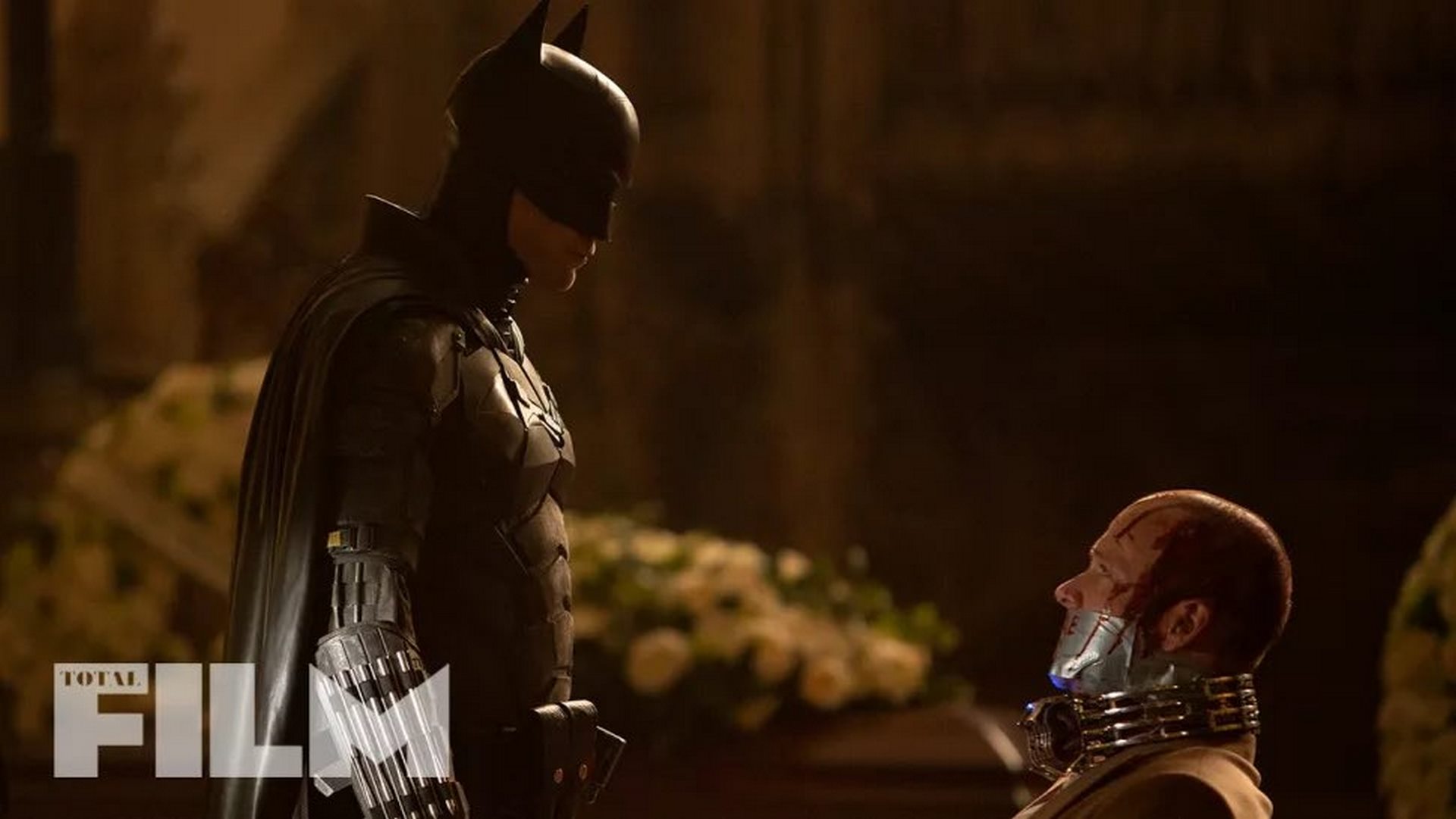 تصویر بتمن از فیلم The Batman در مقابل شخصی که بمب در گردن‌اش فعال است 