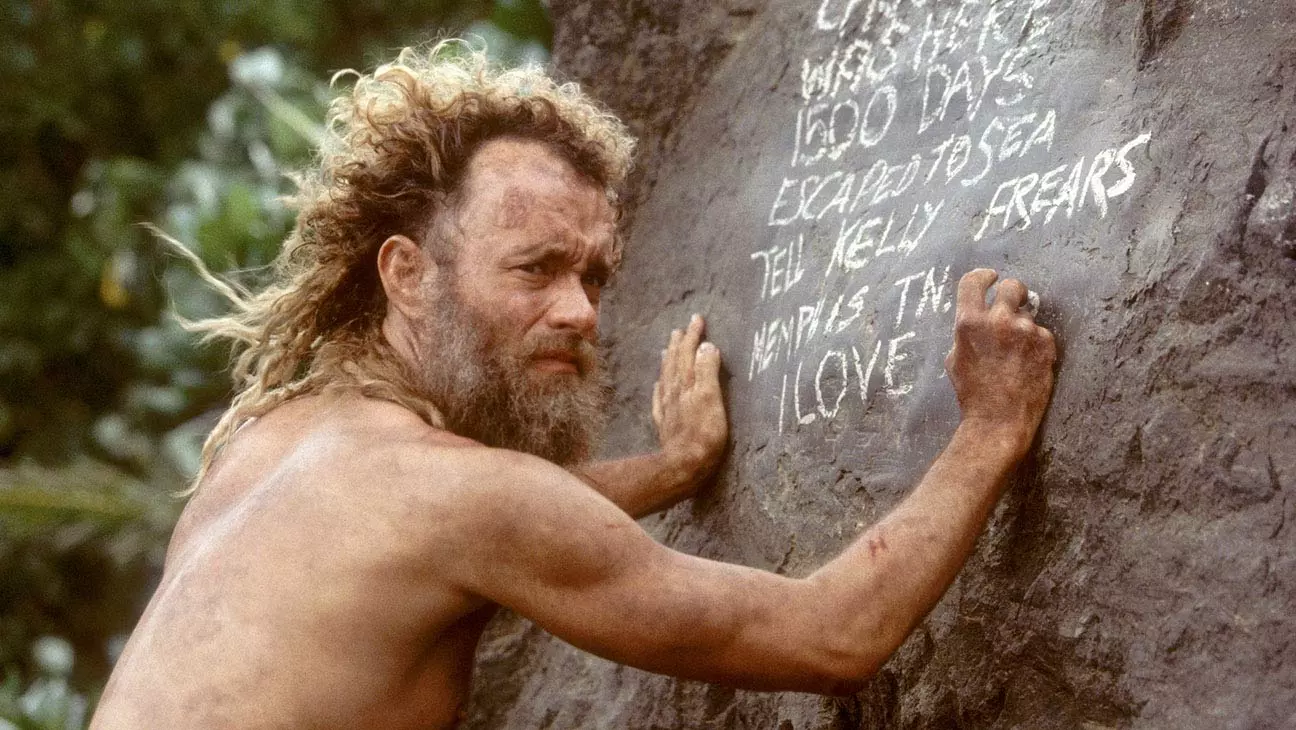 تام هنکس در نقش چاک نولند در فیلم دورافتاده درحال نوشتن روی سنگ
