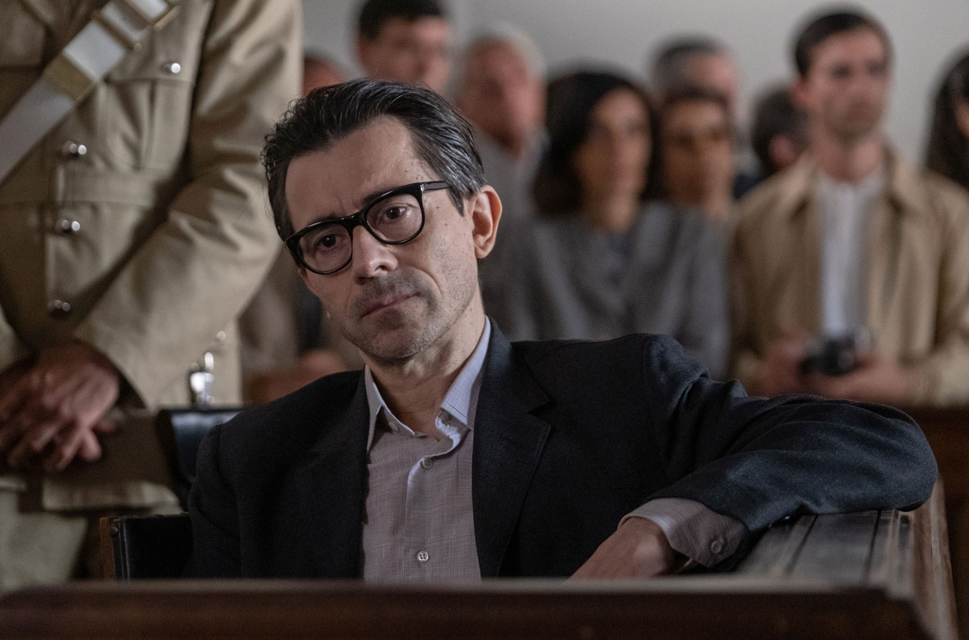 لوئیجی لوکاسیو نشسته در یک دادگاه در نقش آلدو برِیبَنتی در حالی که یک سرباز را بالای سر خود می‌بیند در فیلم ارباب مورچه‌ها 