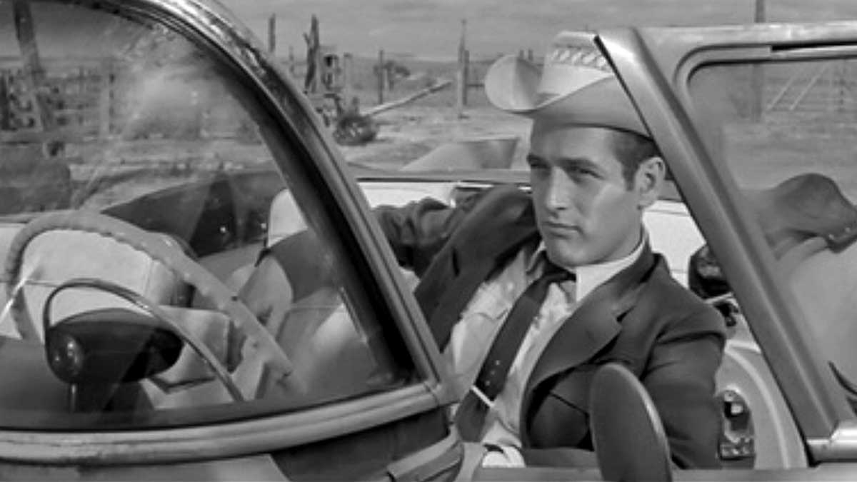 مرد با کلاه و کراوات پشت فرمان ماشین در فیلم درام وسترن Hud، محصول سال ۱۹۶۳ میلادی با بازی پل نیومن