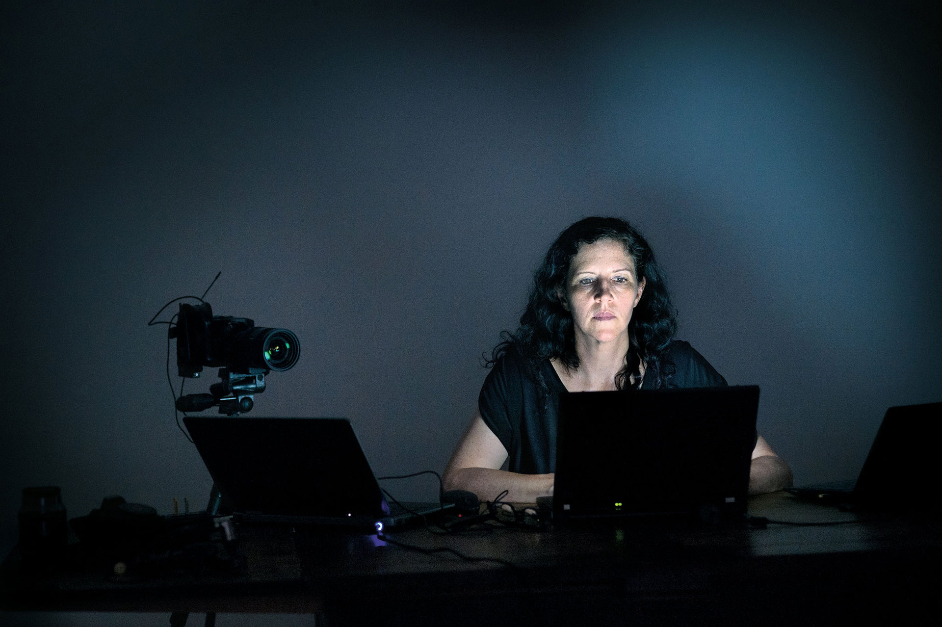 لورا پویتراس مستندساز نشسته در تاریکی پشت لپ‌تاپ و کنار یک دوربین