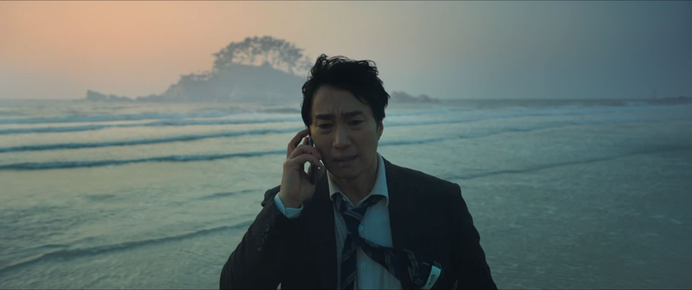 پارک هائه-ایل ایستاده مقابل دریا در حال گوش دادن به صدای تلفن همراه در نمایی از فیلم عزم رفتن به کارگردانی پارک چان ووک