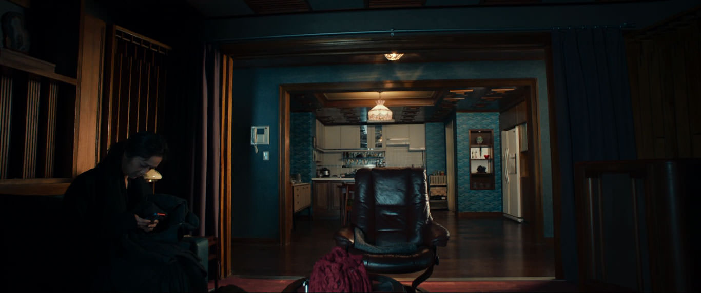 تانگ وی نشسته روی یک مبل داخل یک خانه در حالی که به صفحه‌ی یک گوشی تلفن همراه نگاه می‌کند در صحنه‌ای از فیلم عزم رفتن به کارگردانی پارک چان ووک