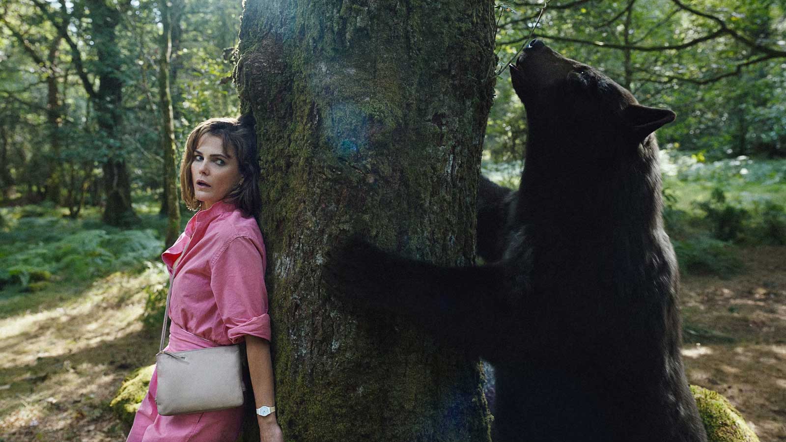 تکیه زن با لباس صورتی به درخت در جنگل فیلم Cocaine Bear (خرس کوکائینی)، یکی از مورد انتظارترین فیلم های ۲۰۲۳