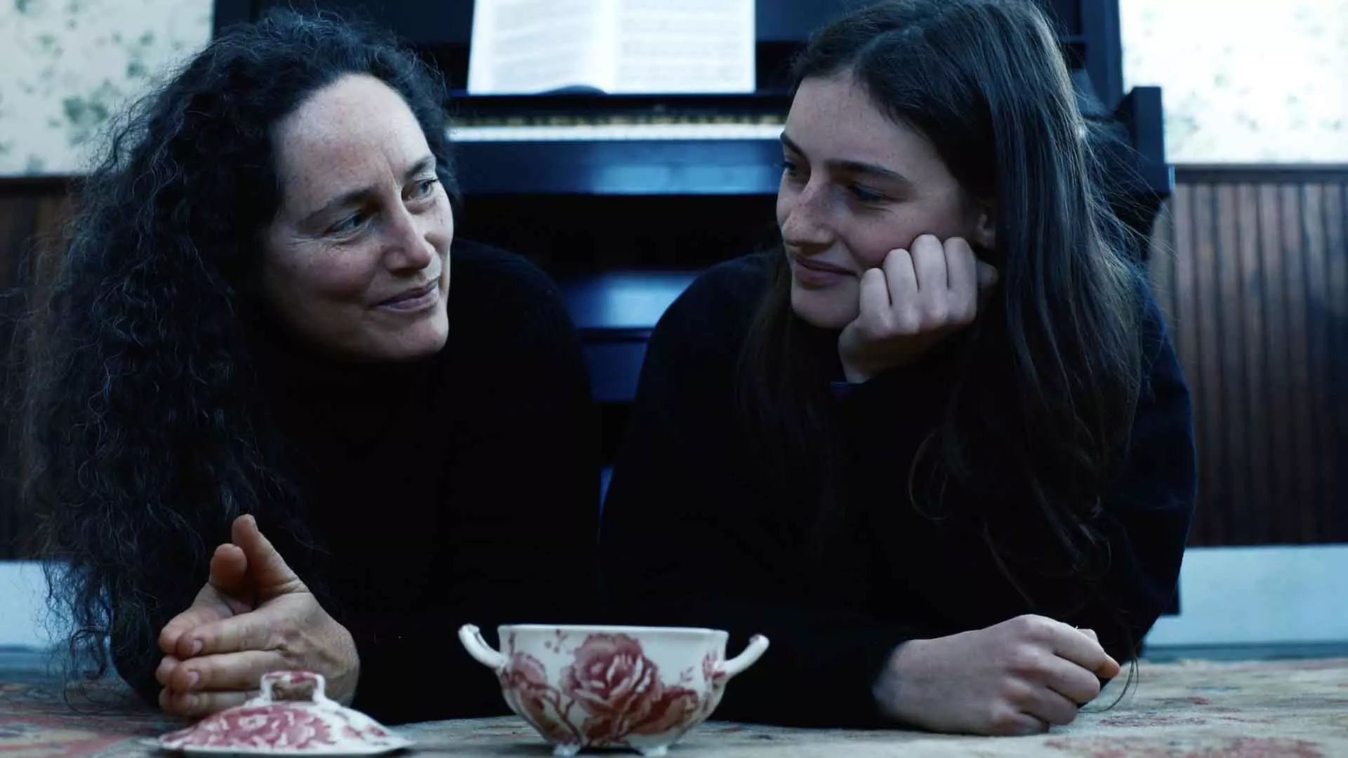 دو زن در فیلم Hellbender با لباس مشکی کنار هم دراز کشیدند و با هم حرف می‌زنند