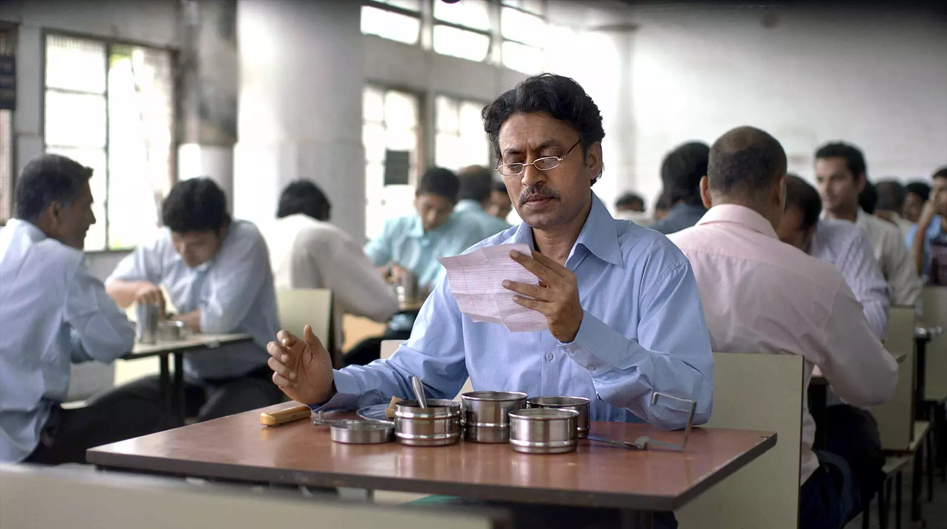 عرفان خان درحال خواندن نامه ای که داخل ظرف غذایش قرار داشته است در فیلم ظرف ناهار
