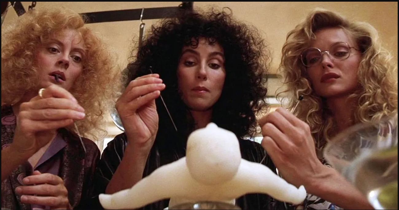 چر، میشل فایفر و سوزان ساراندون در فیلم جادوگران ایستویک درحال فرو کردن سوزن داخل یک عروسک وودو