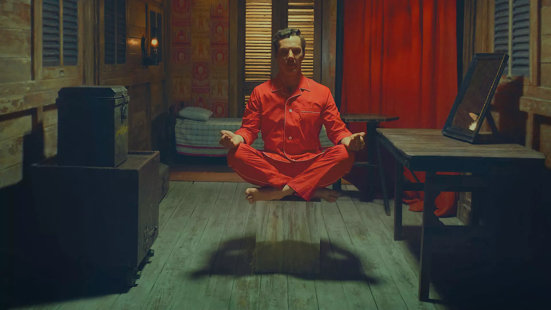 بندیکت کامبربچ با لباس خواب قرمز روی سکویی نشسته است جوری که انگار بین زمین و هوا معلق است و مدیتیشن می‌کند در نمایی از فیلم کوتاه داستان شگفت‌انگیز هنری شوگر به کارگردانی وس اندرسون