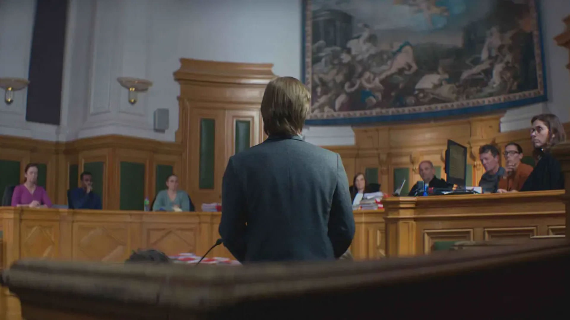 ساندرا هولر ایستاده پشت به دوربین رو به مقامات دادگاه در نمایی از فیلم آناتومی یک سقوط به کارگردانی ژوستین تریه
