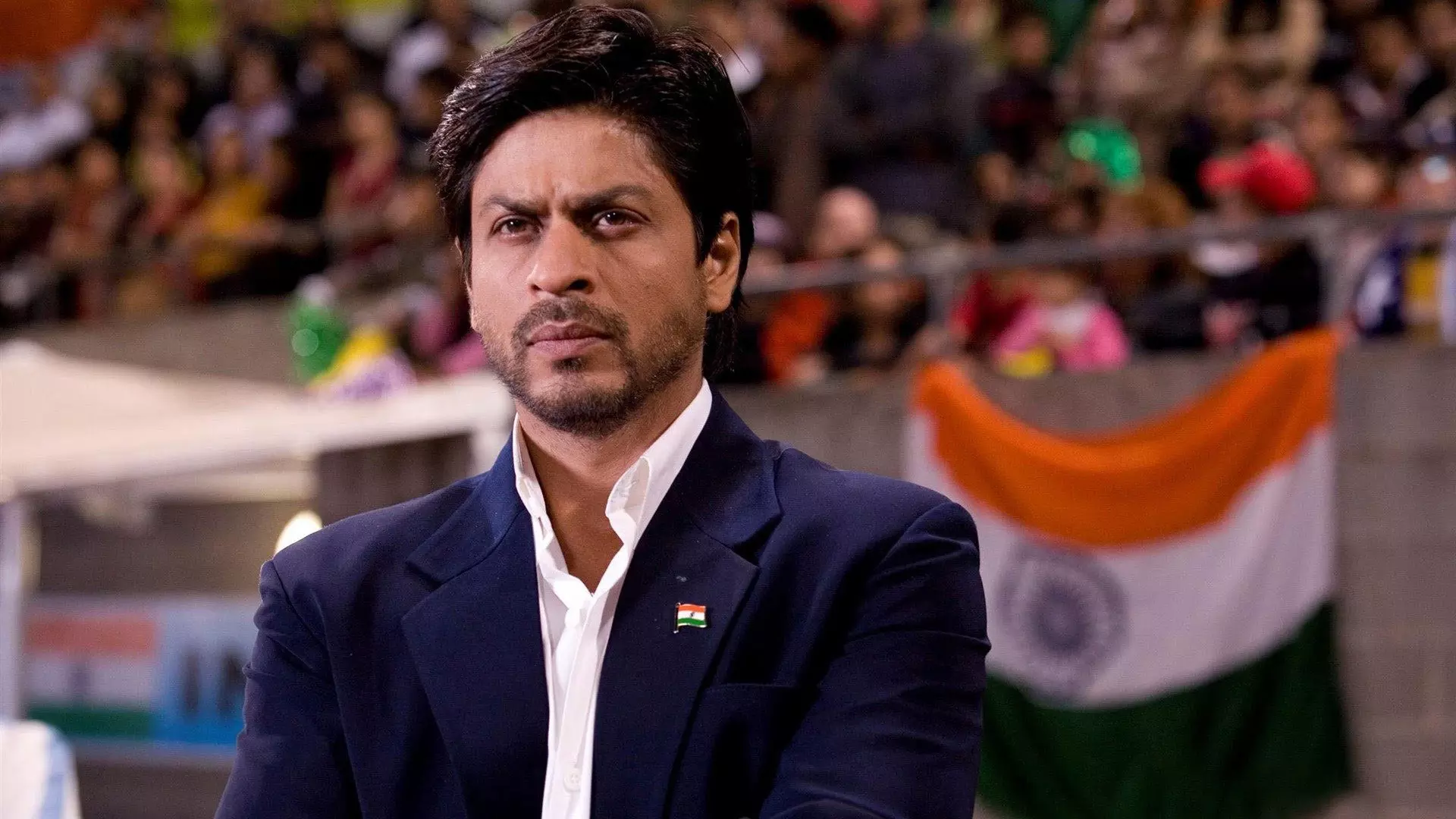 شاهرخ خان در نقش مربی تیم هند در فیلم هند به پیش با تصویری از پرچم هند در پس زمینه