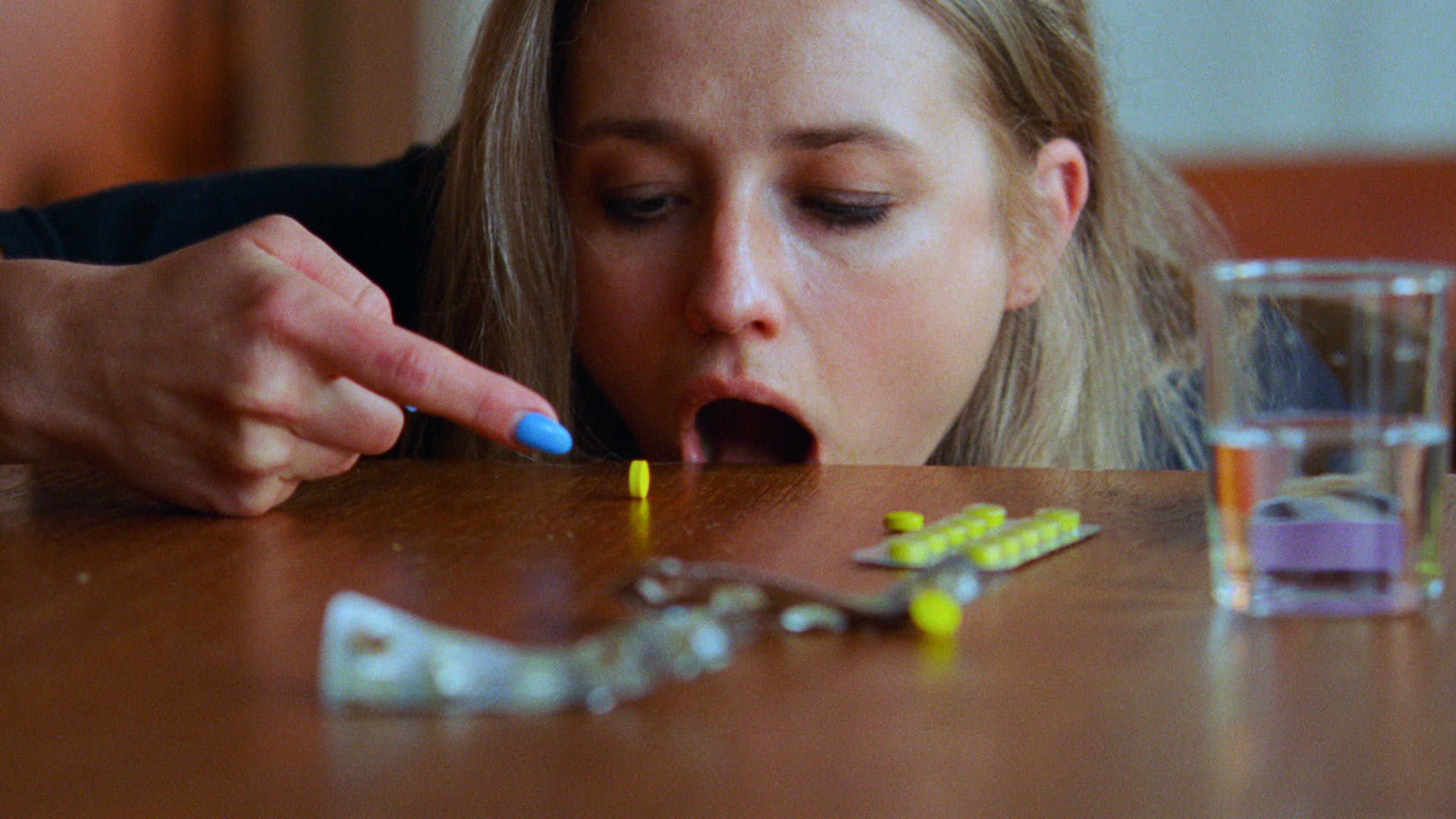 کریستین کوجات-تورپ در صحنه ای از فیلم I'm Sick of Myself اثر کریستوفر بورگلی یک قرص زرد می خورد.