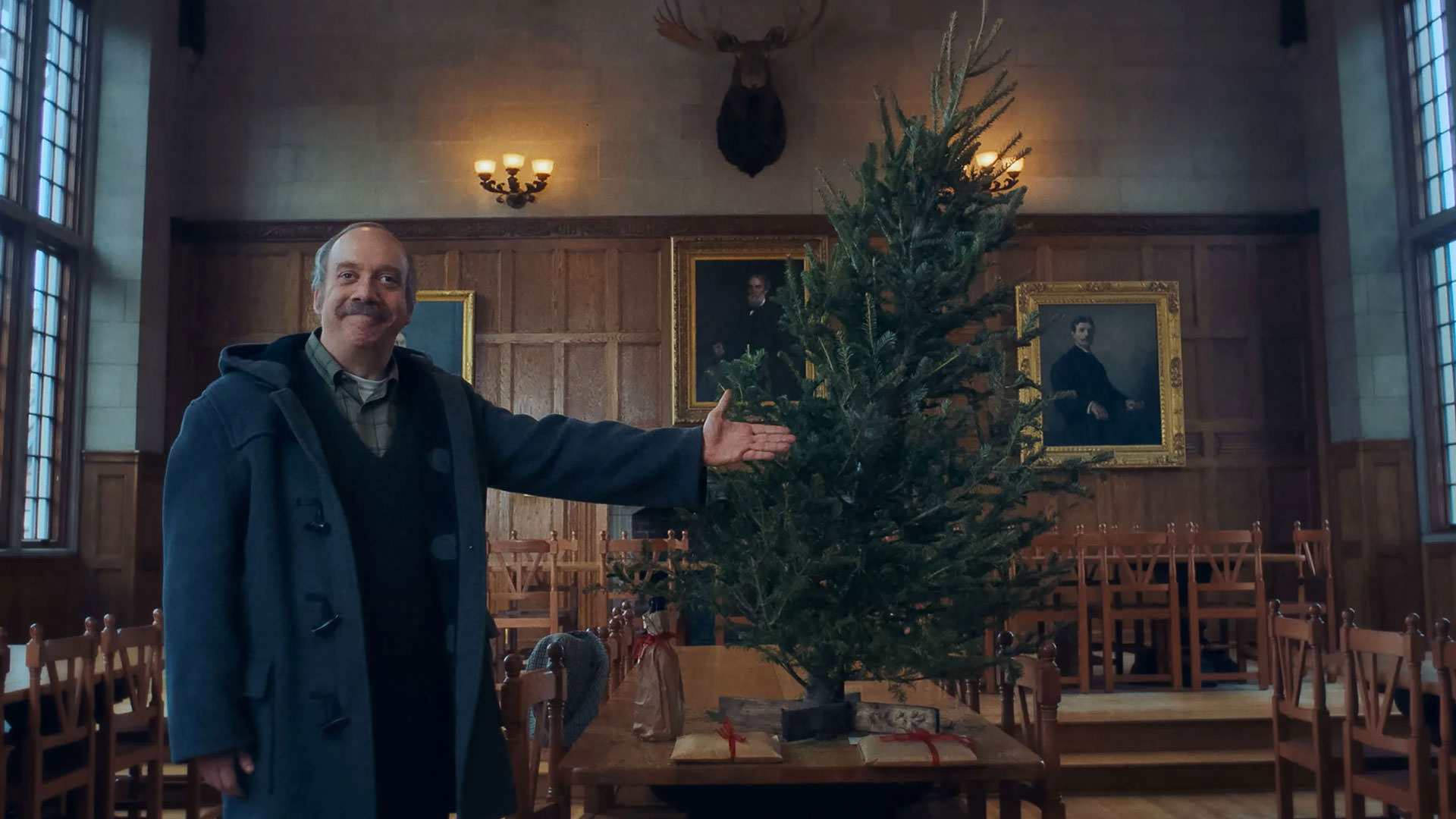 پل جیاماتی با چهره ای شاد در کنار درخت کریسمس پیچ خورده و تزئین نشده در صحنه ای از فیلم بازماندگان به کارگردانی الکساندر پین ایستاده است.