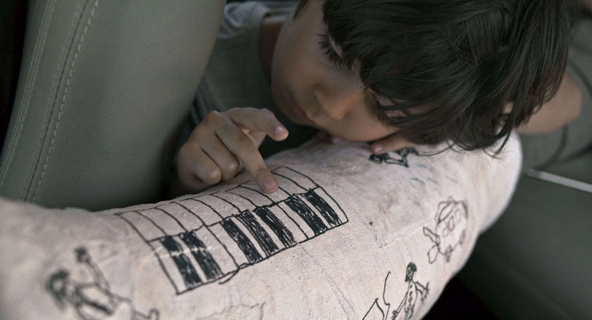 رایان سرلک در حال بازی با یک کیبورد نقاشی‌شده روی گچ پا در نمایی از فیلم جاده خاکی به کارگردانی پناه پناهی