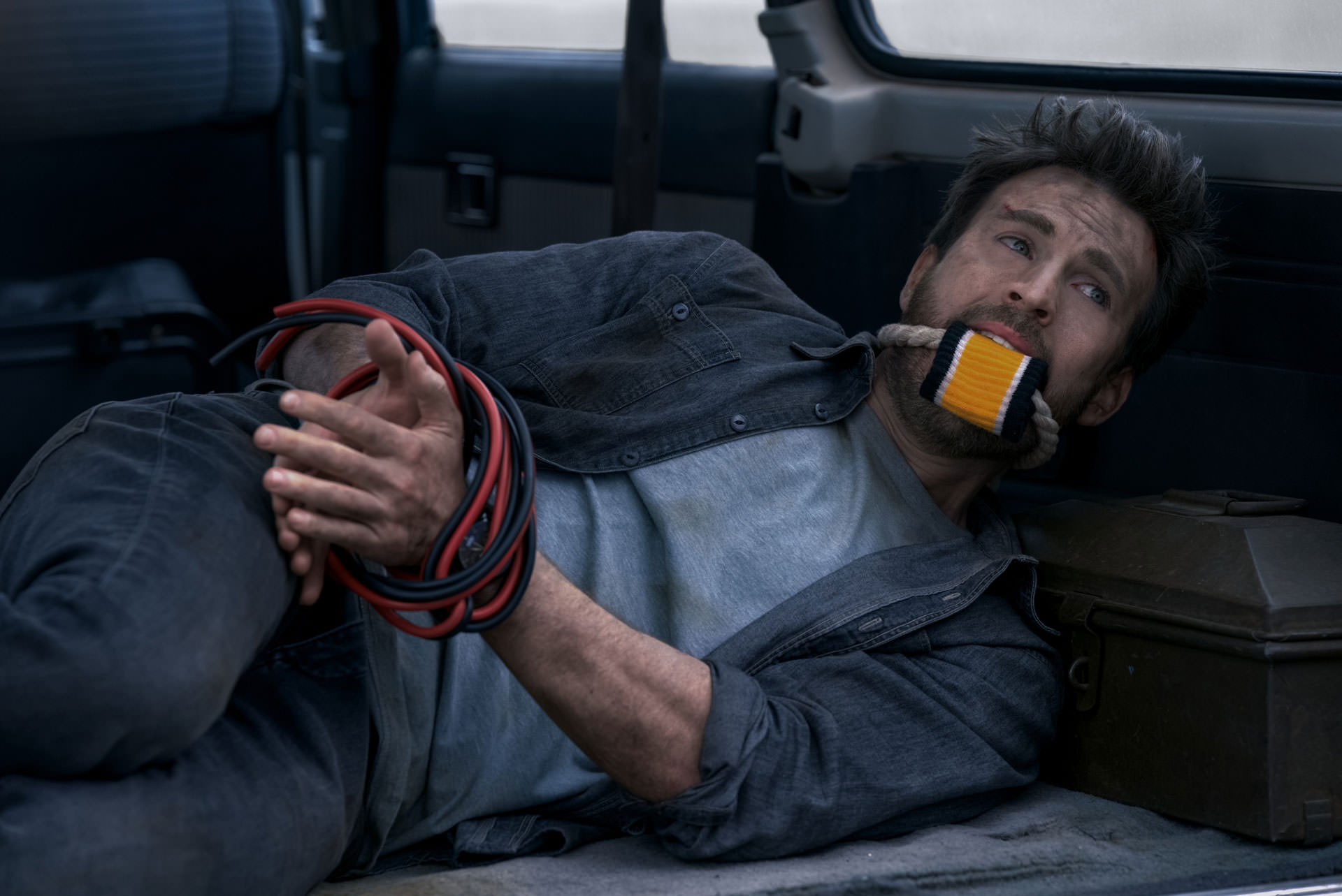 Chris Evans allongé les mains et la bouche fermées sur le siège arrière d'une voiture dans une scène du film Ghost réalisé par Dexter Fletcher.
