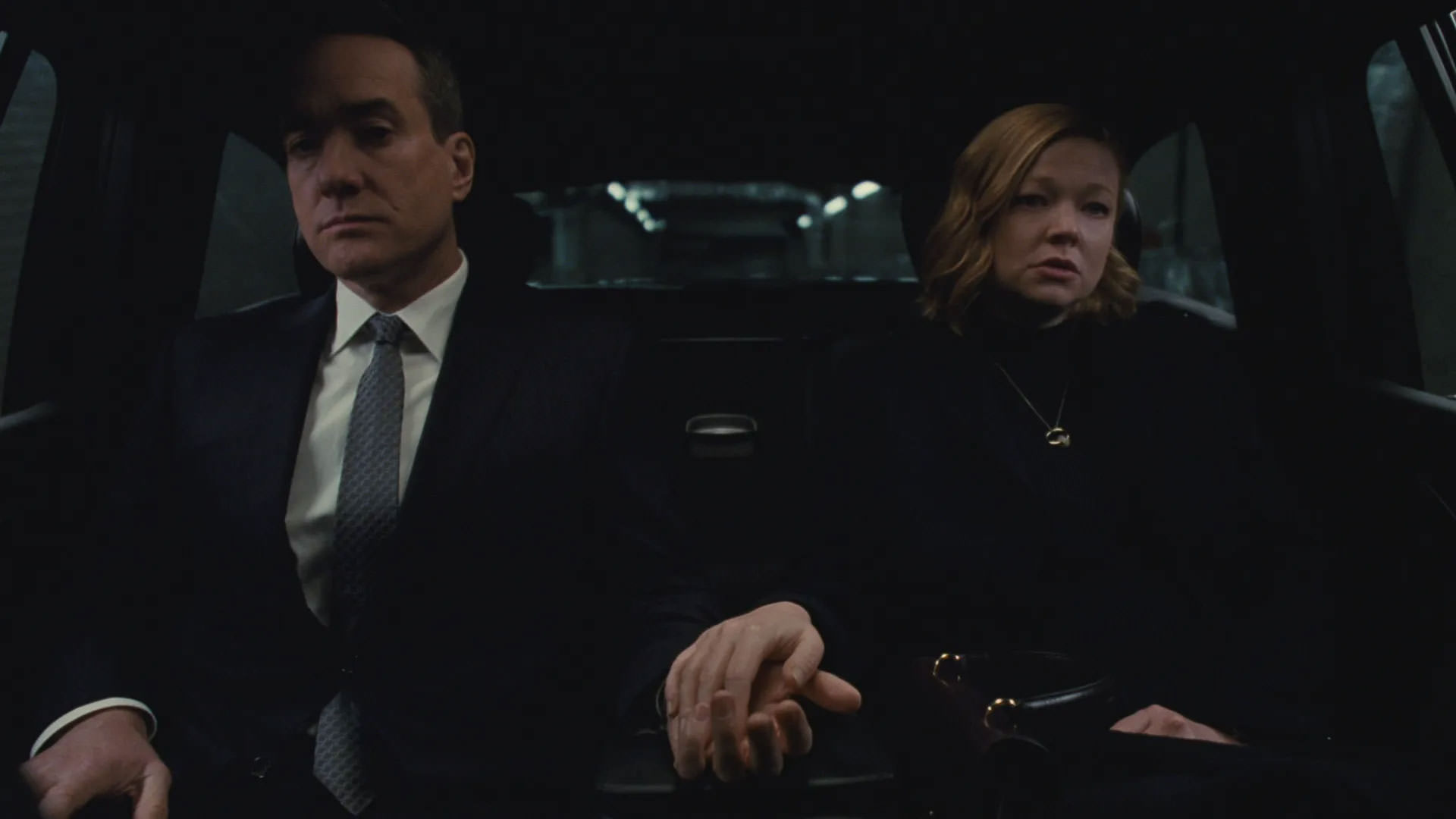 سارا اسنوک و متیو مک‌فدین با لباس‌هایی تیره نشسته کنار یکدیگر روی صندلی عقب یک ماشین در حالی که دست‌هاشان را روی یک‌دیگر قرار داده‌اند در نمایی از سریال وراثت