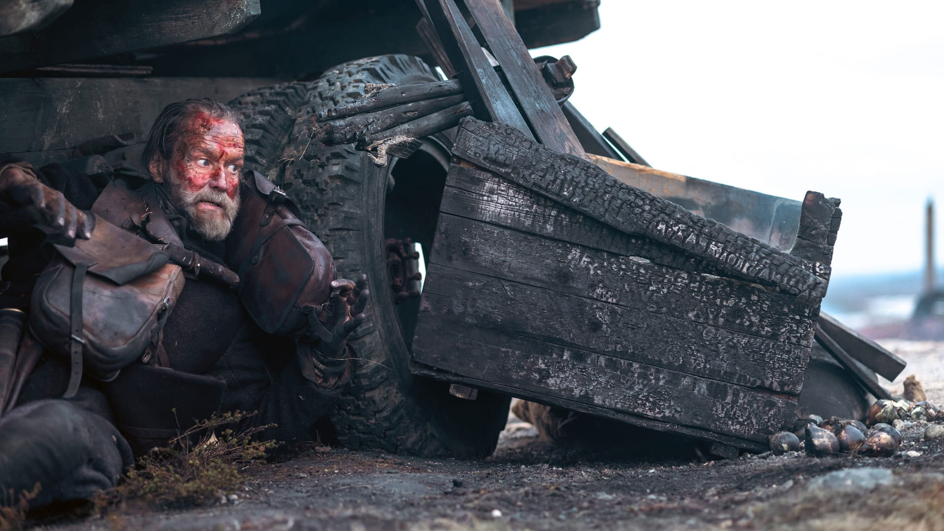 یک مرد مسن که پشت یک ماشین سوخته پناه گرفته است در نمایی از فیلم سیسو به کارگردانی جلماری هلندر