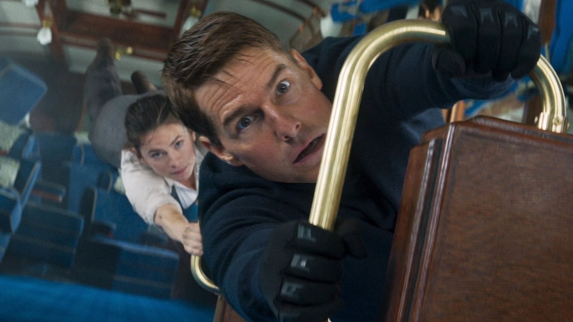 تام کروز و هیلی آتول در صحنه قطار از Mission: Impossible – Dead Reckoning Part One از صندلی واگن قطار در حال سقوط آویزان شده اند.