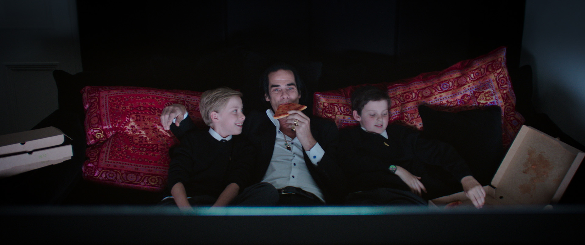 نیک کیو و پسرانش در حال خوردن پیتزا و تماشای تلویزیون در مستند 20000 Days
