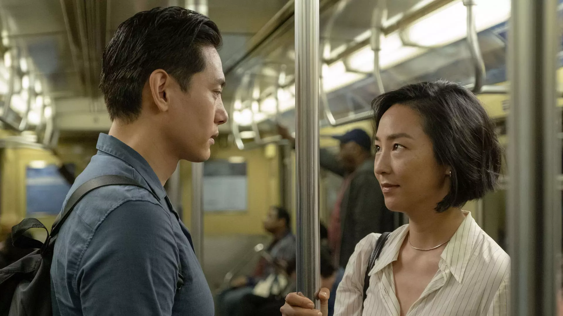 گرتا لی و تئو یو ایستاده مقابل یکدیگر داخل واگن یک مترو در نمایی از فیلم زندگی‌های پیشین به کارگردانی سلین سانگ