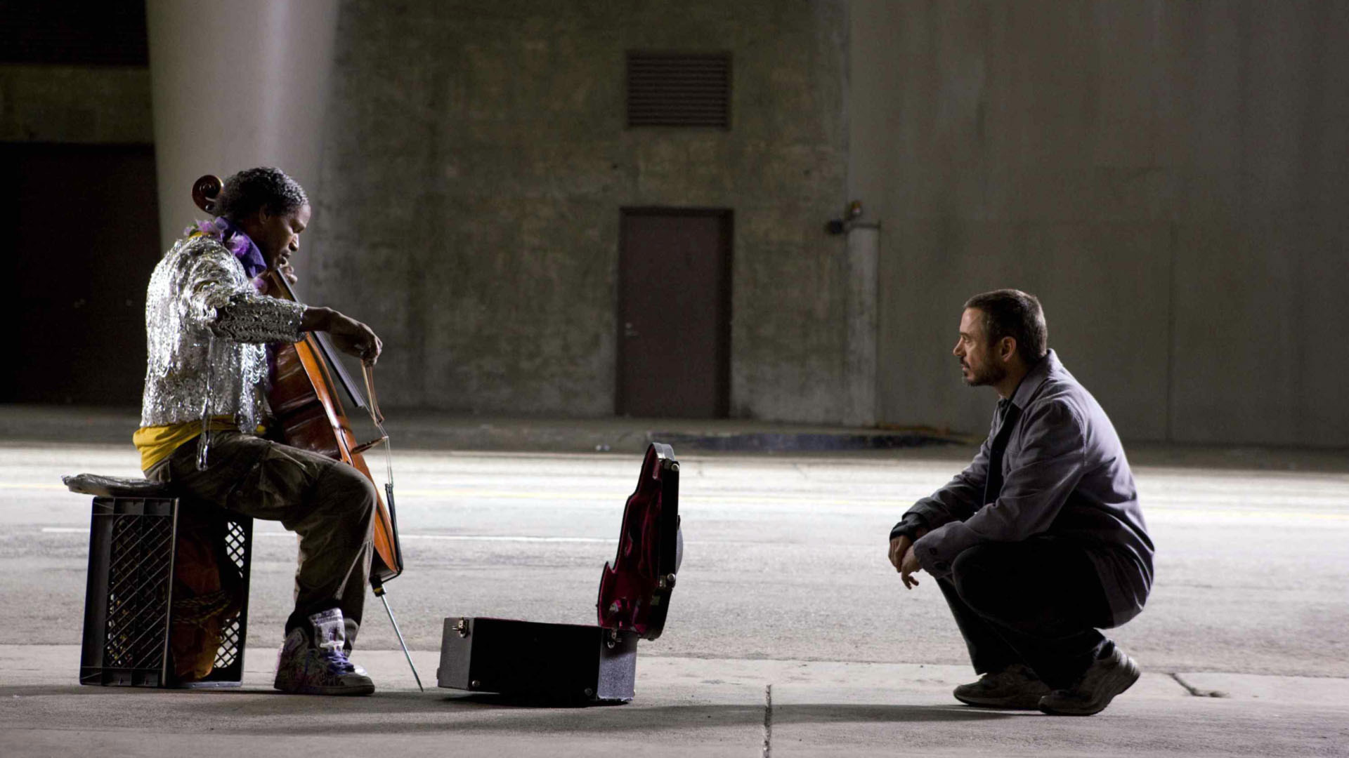 رابرت داونی جونیور چمباتمه زده درحال تماشای نوازندگی مرد بی خانمان در فیلم تک نواز