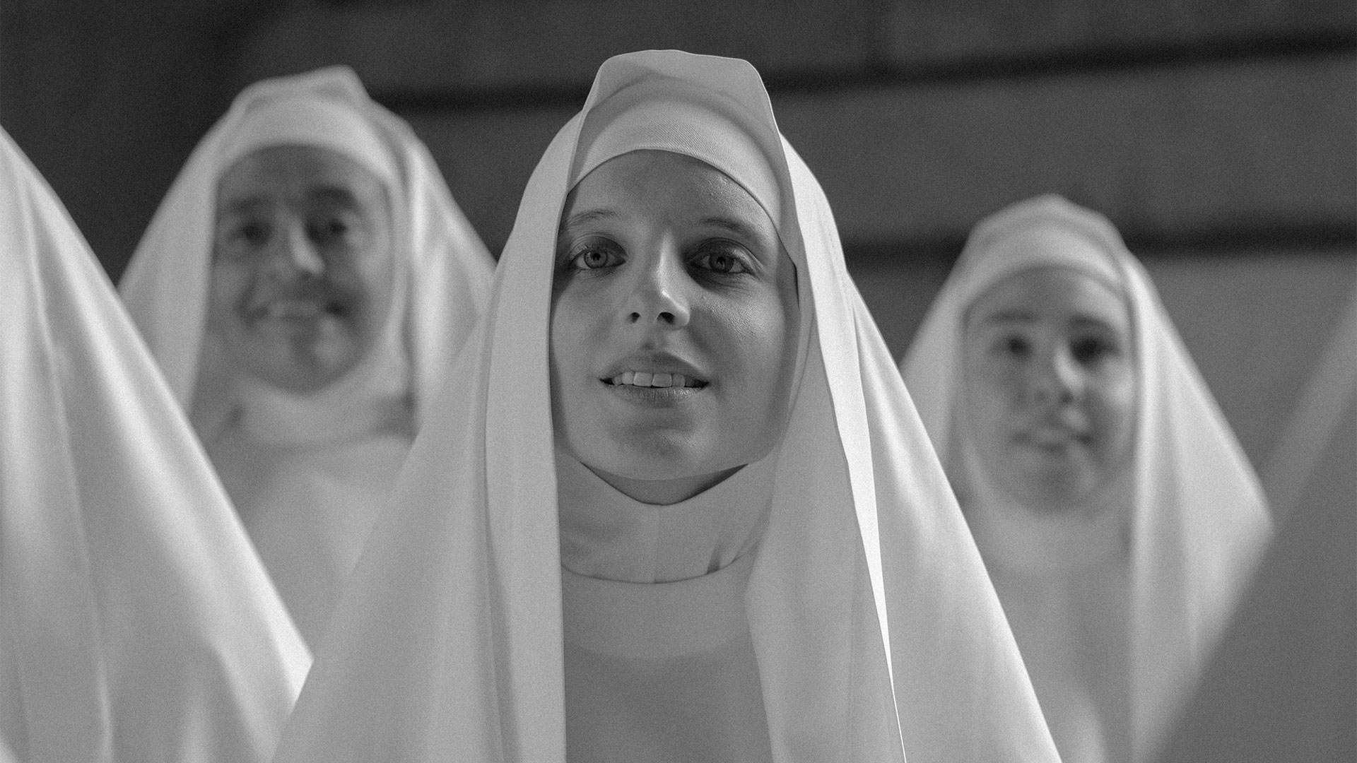 پائولا لاشینگر با لباسی یک‌دست سفید در نقش یک راهبه در میان جمعی از راهبه‌ها در نمایی سیاه و سفید از فیلم کنت به کارگردانی پابلو لارائین
