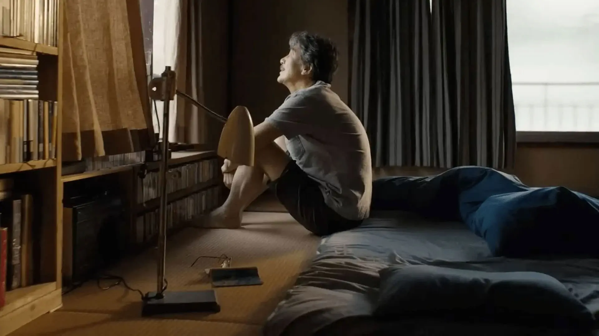 کوجی یاکوشو نشسته روی زمین داخل اتاق رو به یک پنجره به تنهایی در نمایی از فیلم روزهای عالی به کارگردانی ویم وندرس