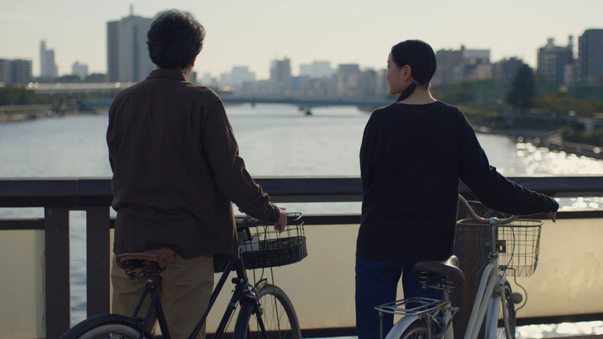 یک پیرمرد و یک دختر نوجوان ایستاده کنار دوچرخه‌هاشان پشت به دوربین در نمایی از فیلم روزهای عالی به کارگردانی ویم وندرس